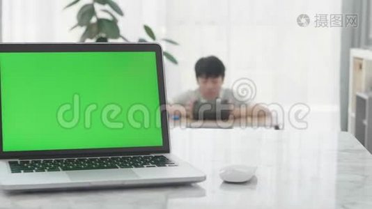 显示绿色色度键屏幕的笔记本电脑站在客厅的桌子上。视频
