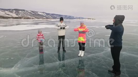 家庭在大自然中冰上做运动。 父亲在冬天训练他的家人。 母女和儿子看着他视频