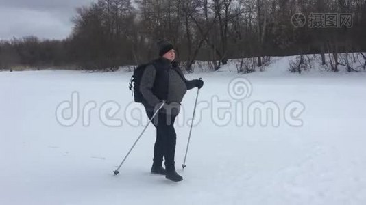 一位老年妇女在冬季森林里用木棍做北欧人的散步。 健康的生活方式观念。 成熟成熟视频