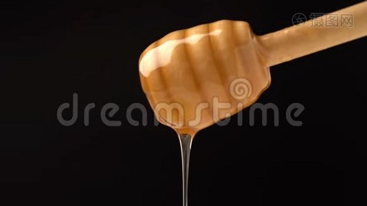 有机蜜滴在黑色背景上的木制蜂蜜勺子上。视频