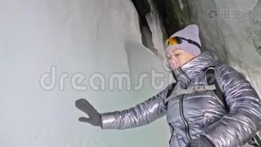 在贝加尔湖冰洞旅行的女人。 去冬岛旅行。 女孩背包客正在冰窟散步。 旅行者看起来视频