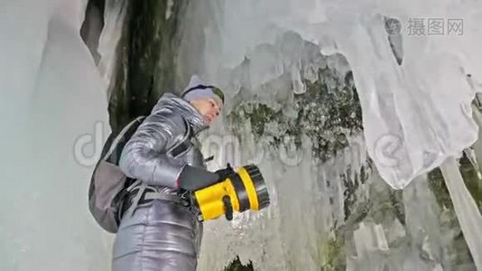 在贝加尔湖冰洞旅行的女人。 去冬岛旅行。 女孩背包客正在冰窟散步。 旅行者看起来视频
