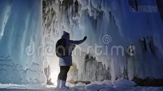 在贝加尔湖冰洞旅行的女人。 去冬岛旅行。 女孩背包客正在冰窟散步。 旅行者看起来视频