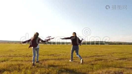 梦想飞翔。快乐童年理念。两个女孩在日落时玩玩具飞机。太阳背景下的孩子们视频