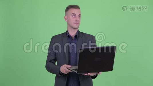 快乐英俊的商人在使用笔记本电脑时会思考问题视频