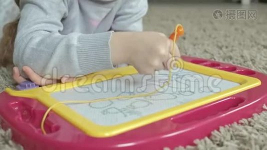 一个红色波浪发的小女孩躺在地板上，画在一块磁板上。 教育过程的概念视频