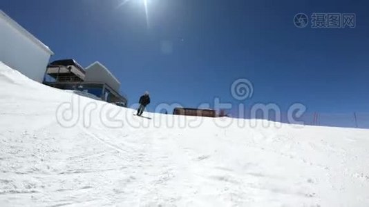 阳光明媚的一天，一个身穿黑色装备、戴着滑雪杆的白色头盔的宽角男滑雪者骑在雪坡上视频