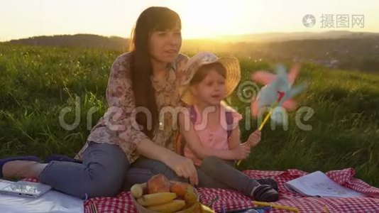 母亲和女儿在日落时在山上野餐。视频