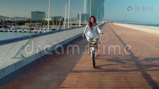 穿着蓝色连衣裙的亚洲模特骑着白色自行车在海上露台上视频