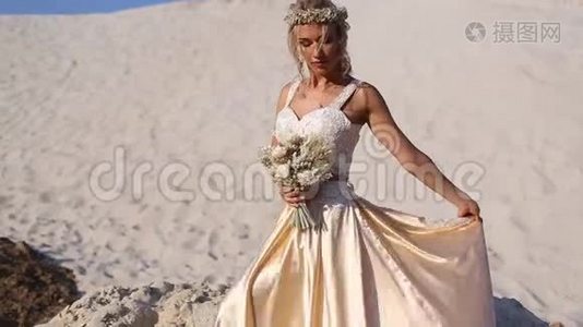 美丽的新娘穿着时尚的飞行服装和花环在迪拜的大沙漠。视频