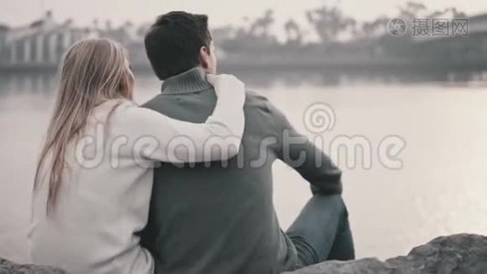 恋爱中的情侣坐在草地上拥抱在公园里视频