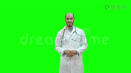 快乐的医生微笑着看着绿色屏幕上的相机，Chroma键。视频