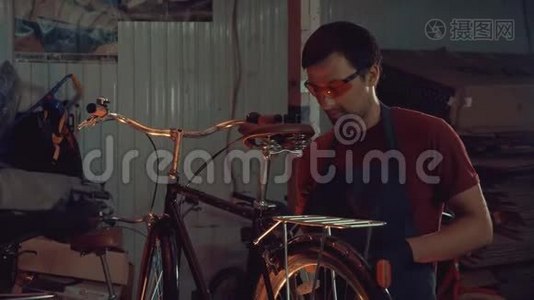 主题小企业自行车修复.. 年轻的白种人黑发男子戴着安全眼镜、手套和围裙，使用手工工具修理视频