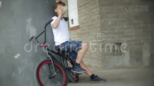 男孩坐在BMX自行车上，听智能手机上的音乐视频