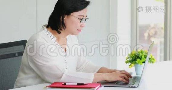 亚洲女商人在办公室里用笔记本电脑。视频