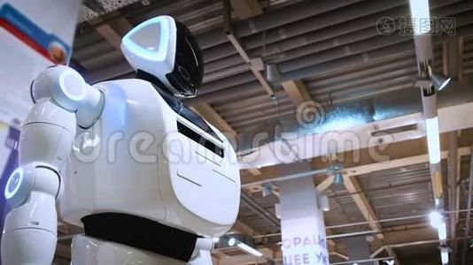 新型现代白色机器人的肖像.. 机器人转过头，看着摄像机。 机器人及高科技展览视频