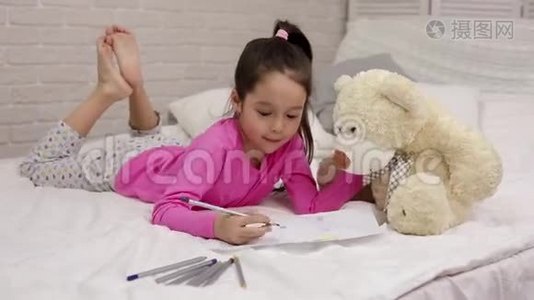 可爱的小女孩躺在床上画画。视频