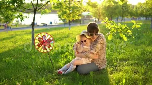 母亲和女儿在日落时快乐地一起在草地上玩耍。视频