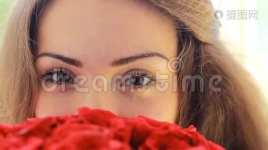 一个年轻美丽的女人带着一束红色玫瑰花的肖像。视频