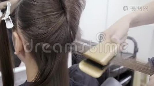 理发师在美容院为一个有深色头发的女孩做头发分层视频