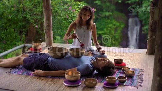 一位亚洲圣药大师为一位年轻的客户表演藏碗治疗仪式的女子拍摄的超慢镜头视频