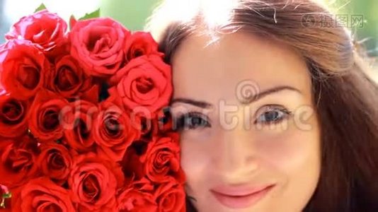 一个年轻美丽的女人带着一束红色玫瑰花的肖像。视频
