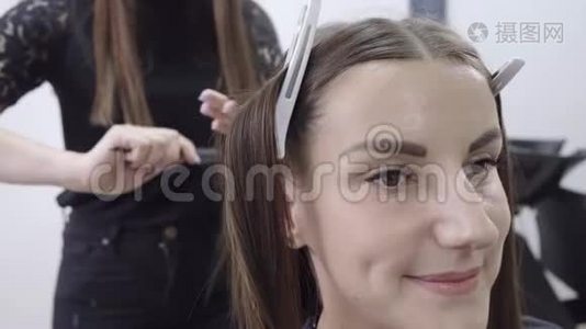 理发师在美容院为一个有深色头发的女孩做头发分层视频