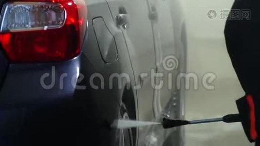 洗车机清洗汽车。 一个洗车工人用水洗一辆车。 特写镜头。视频