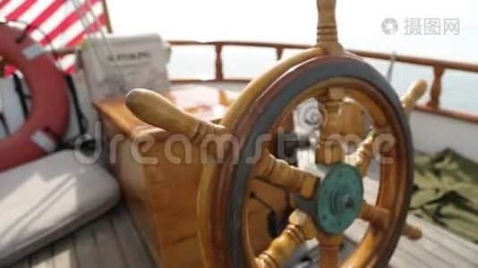 在阳光明媚的一天，一艘木制古董帆船的方向盘和甲板在海洋中航行，展示了木制部件和视频