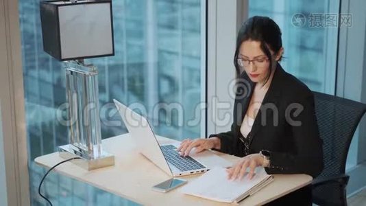 一位年轻的女商人在现代办公室的电脑上工作的画像视频