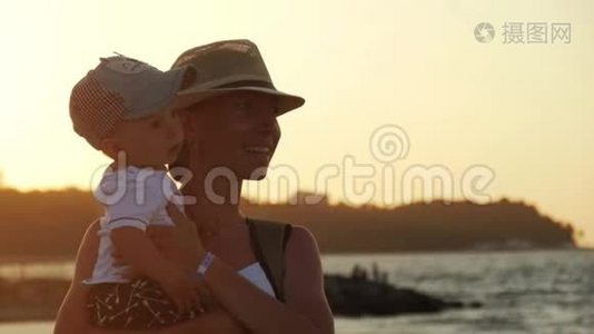 年轻的母亲把儿子抱在海边的怀里。视频