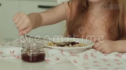 快乐的美丽女孩早餐吃粥，在家的白色厨房里玩得开心视频