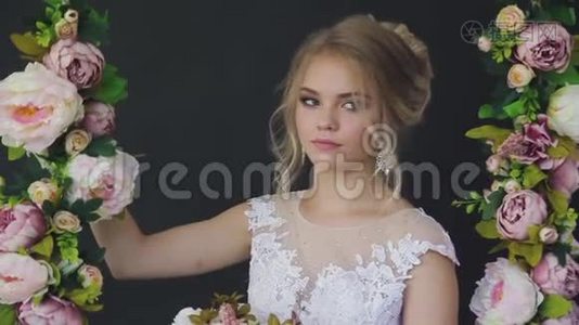 美丽的金发碧眼，穿着一件白色的新娘礼服，靠近一扇窗户，放着一束鲜花视频