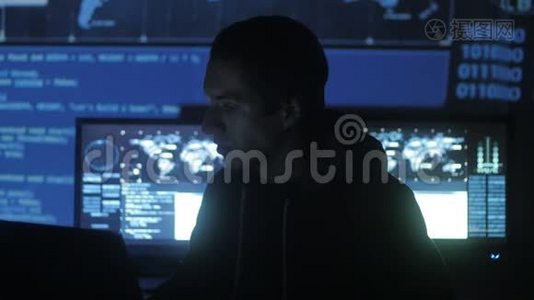 年轻的GeekHacker程序员正在电脑安全中心工作，里面装满了显示屏。视频