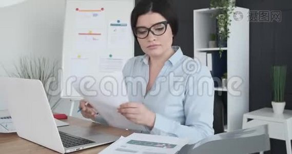 女商人在办公室里拿着文件和笔记本电脑视频
