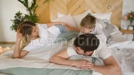 一个小儿子的年轻家庭在卧室里睡觉视频
