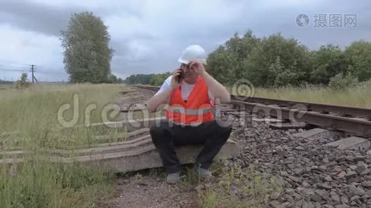 坐在铁路附近的铁路和电话视频