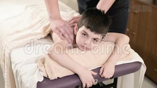 男性理疗师按摩师为躺在按摩床上的小男孩做一个疗愈放松的按摩。 手和手视频