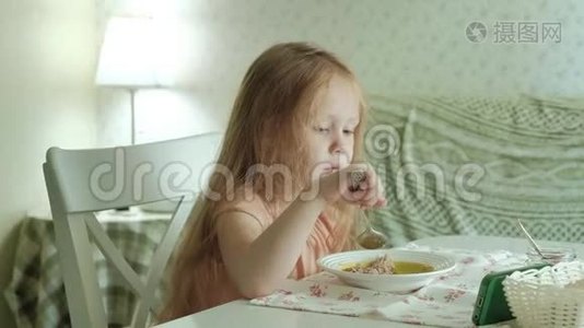 快乐的美丽女孩早餐吃粥，在家的白色厨房里玩得开心视频