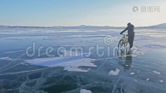 人在冰上骑着自行车走. 骑自行车的人穿着灰色的羽绒服，背包和头盔。 冰的冰视频