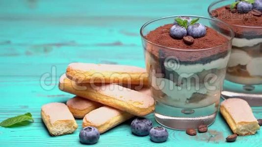 经典的提拉米苏甜点在蓝色木制背景的蓝莓玻璃视频