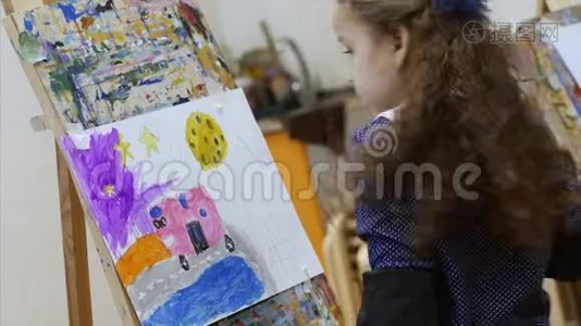 年轻可爱的女艺术家在一个艺术工作室，坐在一个Easel和绘画画布。 绘图过程：视频