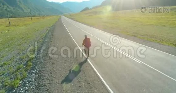 乘坐搭便车游客在沥青路上行走。 夏日的乡村山谷。 背包徒步旅行者。视频