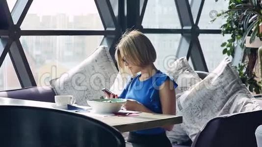 美丽的女人在午餐时休息，坐在咖啡馆里。 商务午餐。 慢动作视频