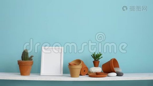 现代客房装饰与相框模型。 白色的架子，贴着青绿色的墙壁，上面有陶器和肉质植物。 手视频