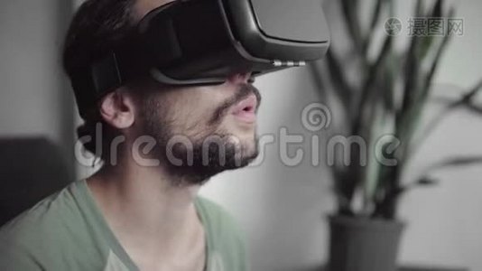 年轻留胡子的嬉皮士使用他的VR耳机显示器与耳机虚拟现实游戏或观看360视频