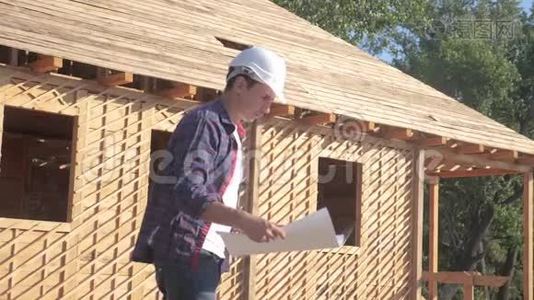 概念建筑构建建筑师慢动作视频.. 戴着头盔的男建筑工人举着一个视频