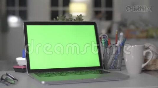 带有绿色屏幕的笔记本电脑。 黑暗的办公室。 完美地放置你自己的图像或视频。视频