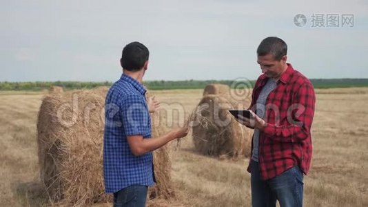 团队农业智慧农业理念.. 在数字平板电脑上研究干草堆的两名男性农民视频