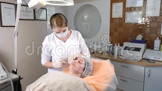 美容诊所。 手套美容师在女性皮肤上进行面部老化注射。 女人得到美容美容美容视频